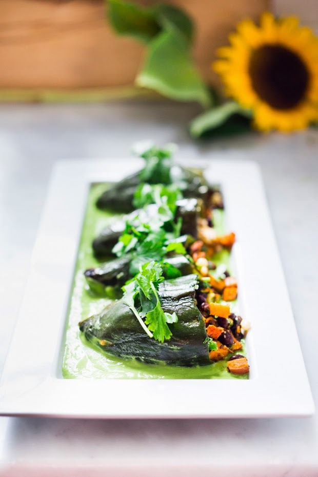 Vegan stuffed poblano peppers filled with sweet potatoes, black beans, corn and cilantro - served over the best thing ever - a flavorful Avocado Crema which is vegan and has no other added oils or fat. | www.feastingathome.com #avocadosauce #avocadocrema #stuffedpoblanos #stuffedpeppers #vegandinner #vegandinnerrecipes