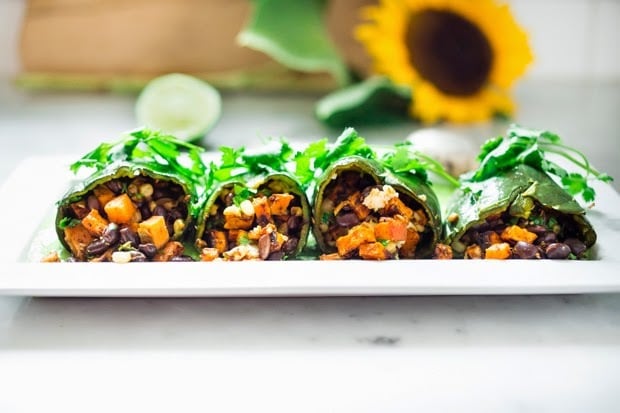 Vegan stuffed poblano peppers filled with sweet potatoes, black beans, corn and cilantro - served over the best thing ever - a flavorful Avocado-Cilantro Sauce which is vegan and has no other added oils or fat. | www.feastingathome.com