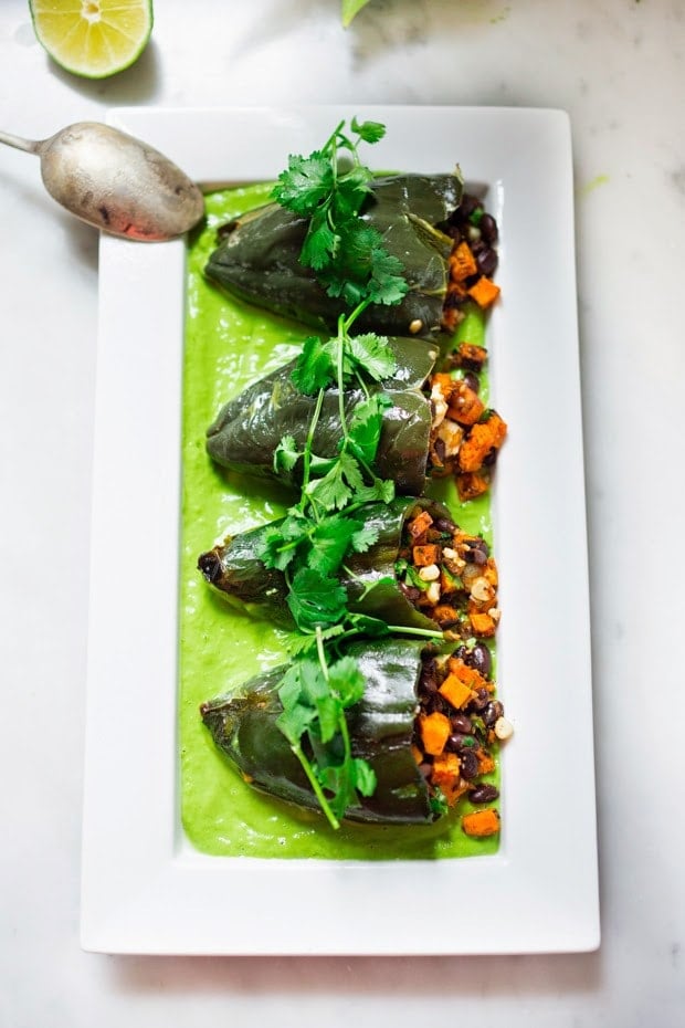 Vegan stuffed poblano peppers filled with sweet potatoes, black beans, corn and cilantro - served over the best thing ever - a flavorful Avocado-Cilantro Sauce which is vegan and oil-free.