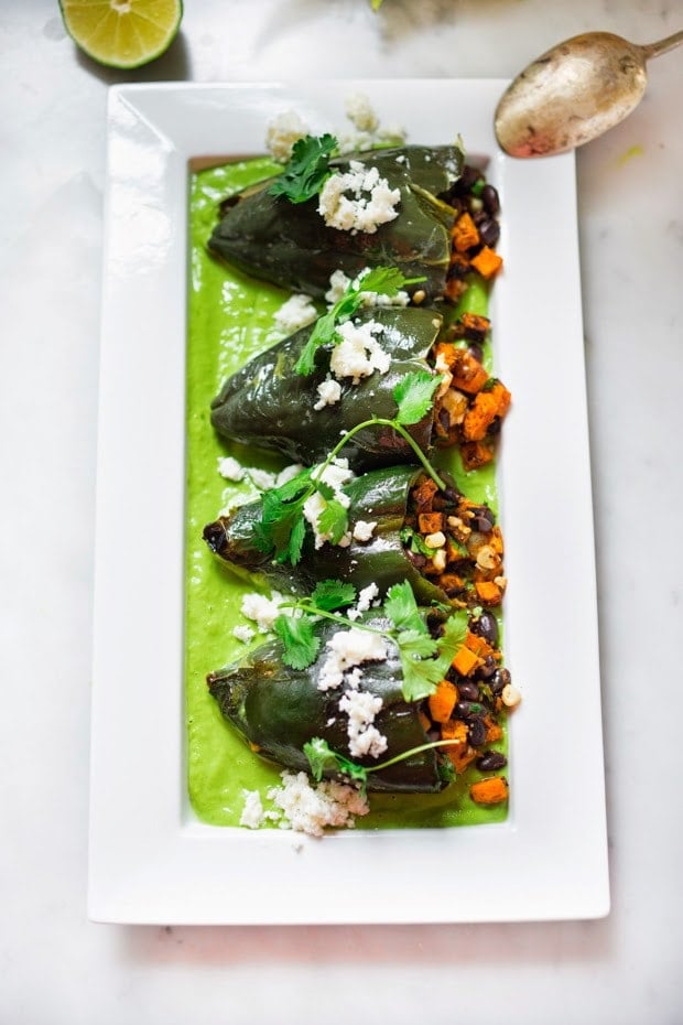 Vegan stuffed poblano peppers filled with sweet potatoes, black beans, corn and cilantro - served over the best thing ever - a flavorful Avocado-Cilantro Sauce which is vegan and has oil-free. | www.feastingathome.com