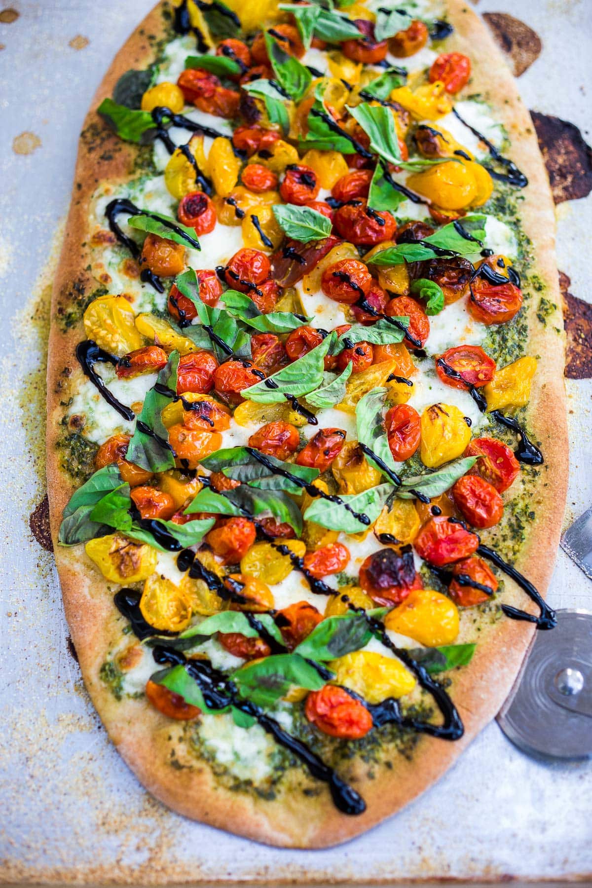 Make a simple, delicious Caprese Pizza with tomatoes, fresh mozzarella, basil leaves and basil oil topped with a balsamic glaze. Use store-bought pizza dough or make your own!