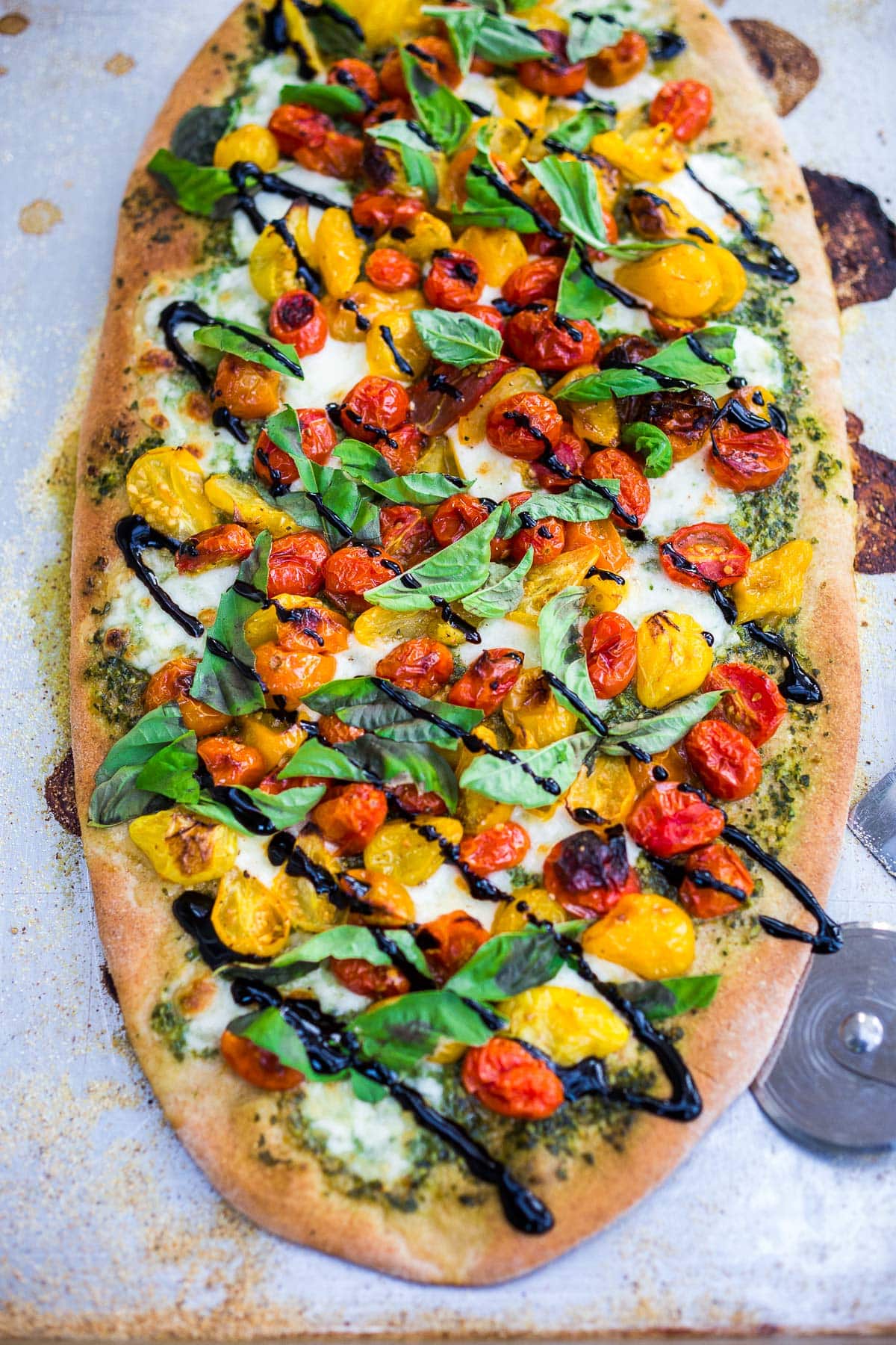 Make a simple, delicious Caprese Pizza with tomatoes, fresh mozzarella, basil leaves and basil oil topped with a balsamic glaze. Use store-bought pizza dough or make your own!