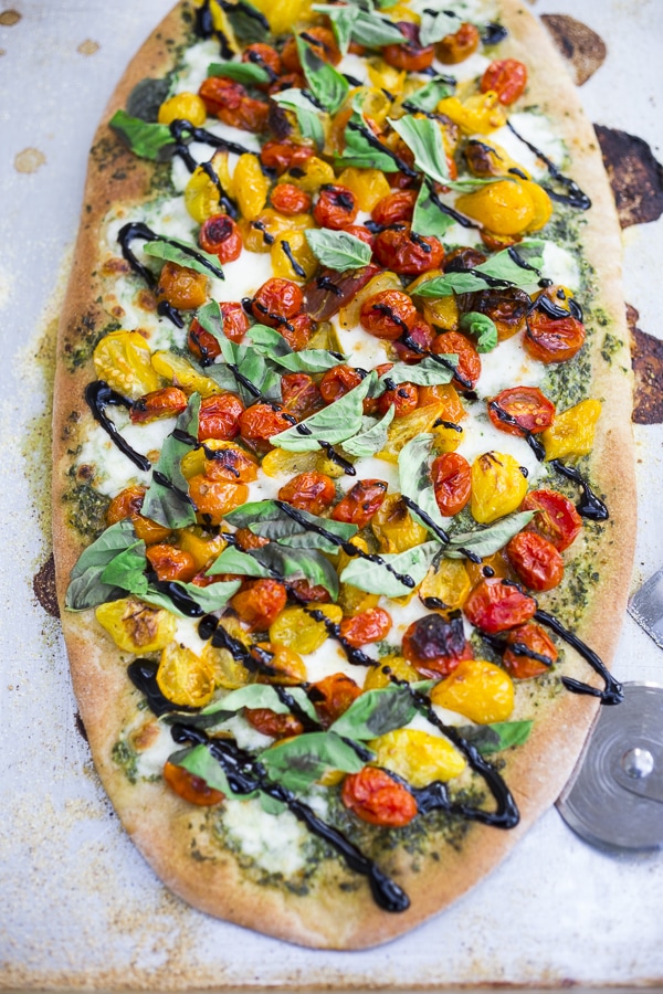 How to make the most delicious Caprese Pizza with cherry tomatoes, mozzarella, basil spread and optional balsamic drizzle. Use store-bought pizza dough or make your own below!