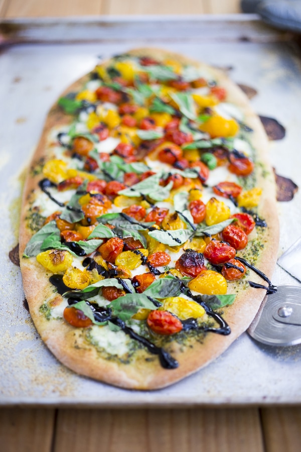 How to make the most delicious Caprese Pizza with cherry tomatoes, mozzarella, basil spread and optional balsamic drizzle. Use store-bought pizza dough or make your own below!