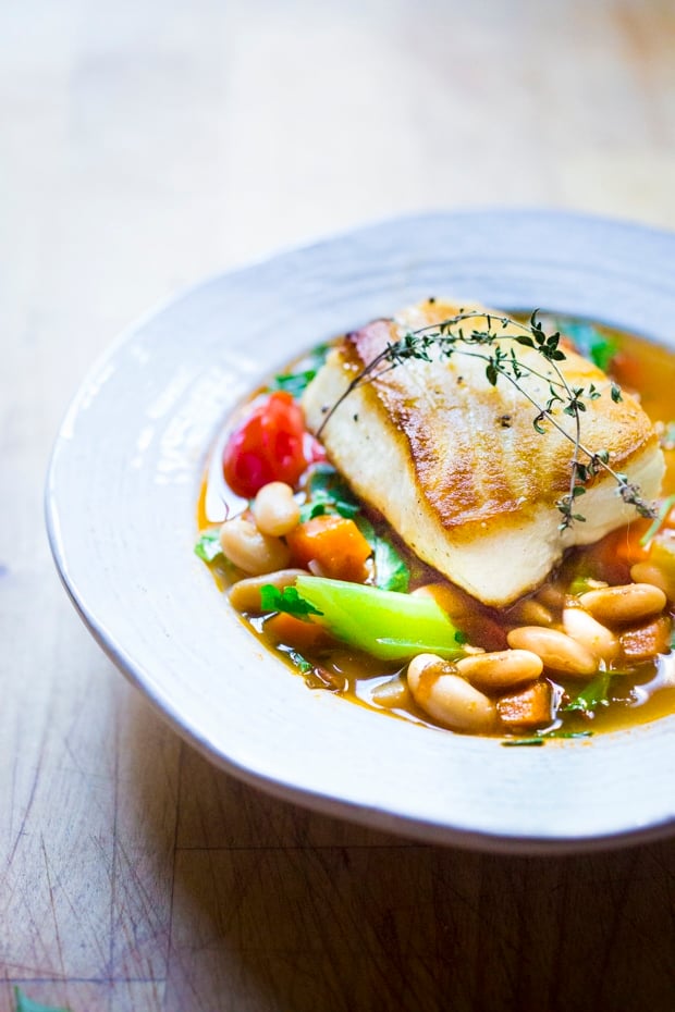 A delicious recipe for Seared Sea Bass over a simple hearty Cannellini Bean Stew. Can be made in 30 minutes. | www.feastingathome.com