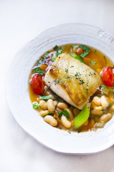 A delicious recipe for Seared Sea Bass over a simple hearty Cannellini Bean Stew. Can be made in 30 minutes. | www.feastingathome.com