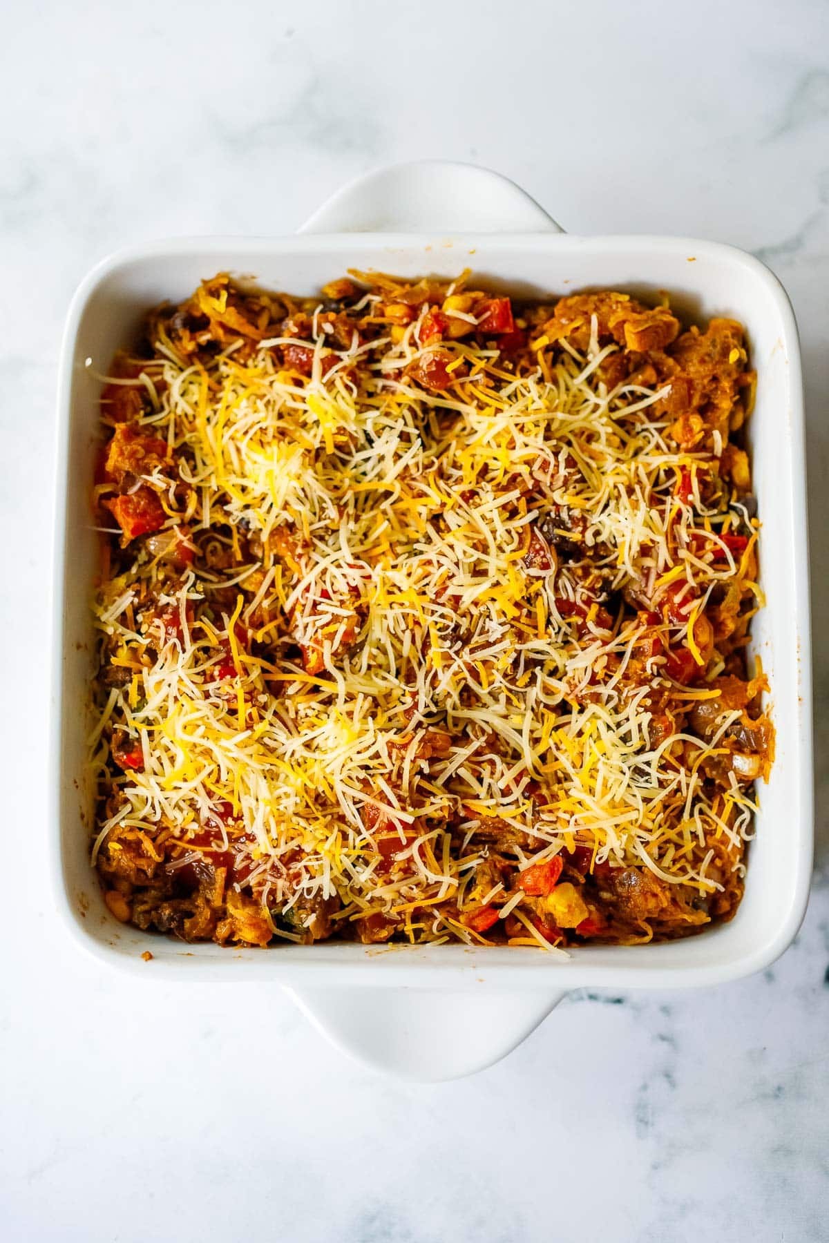 Example of creating a spaghetti squash casserole- filling in a a casserole baking dish, topped with cheese. 