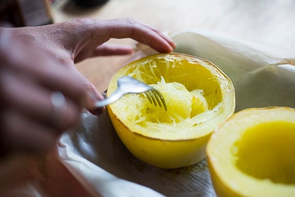 scooping out the cooked spaghetti squash into a bowl. 