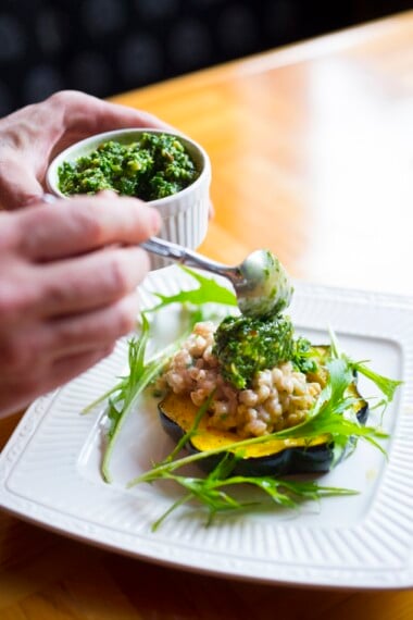 A delicious fall recipe - Roasted Acorn Squash w/ Farro Risotto and Radish Top Pesto- a perfect vegetarian main course, created by chef Tony Brown of Ruins. | www.feastingathome.com | www.feastingathome.com