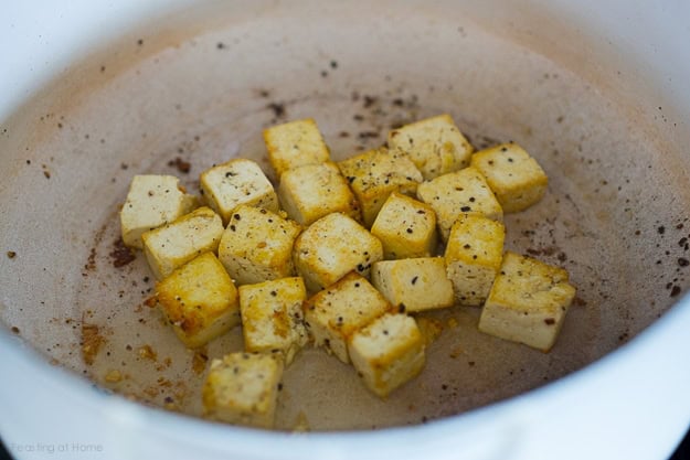 seared crispy tofu cubes in pot with oil and black pepper.