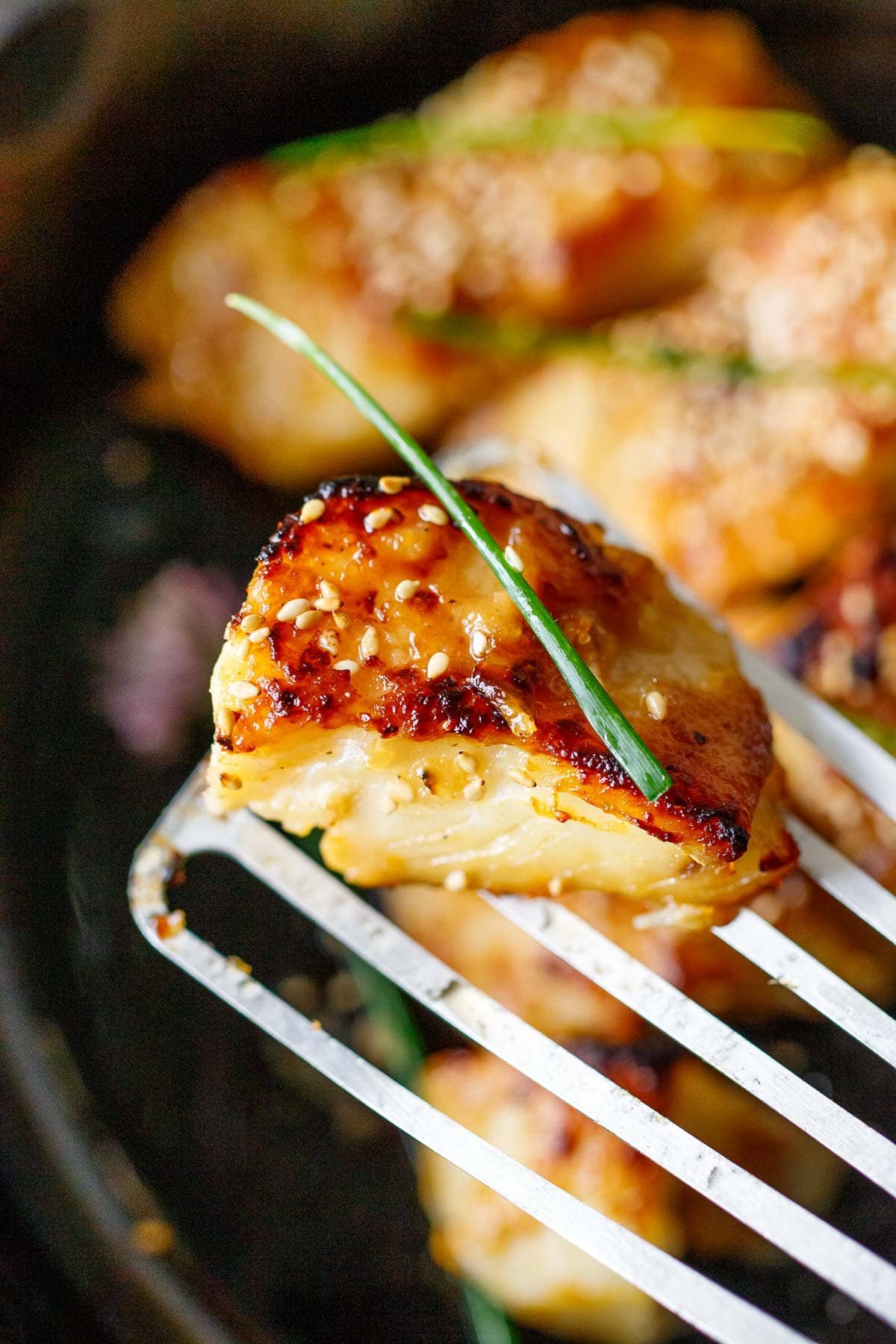 A piece of miso black cod on a metal spatula.
