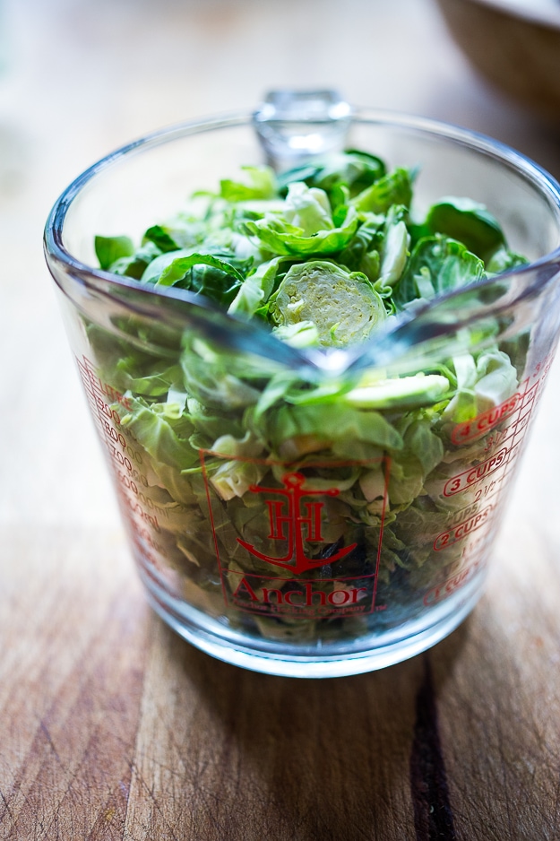 sliced brussels sprouts in a measuring glass.