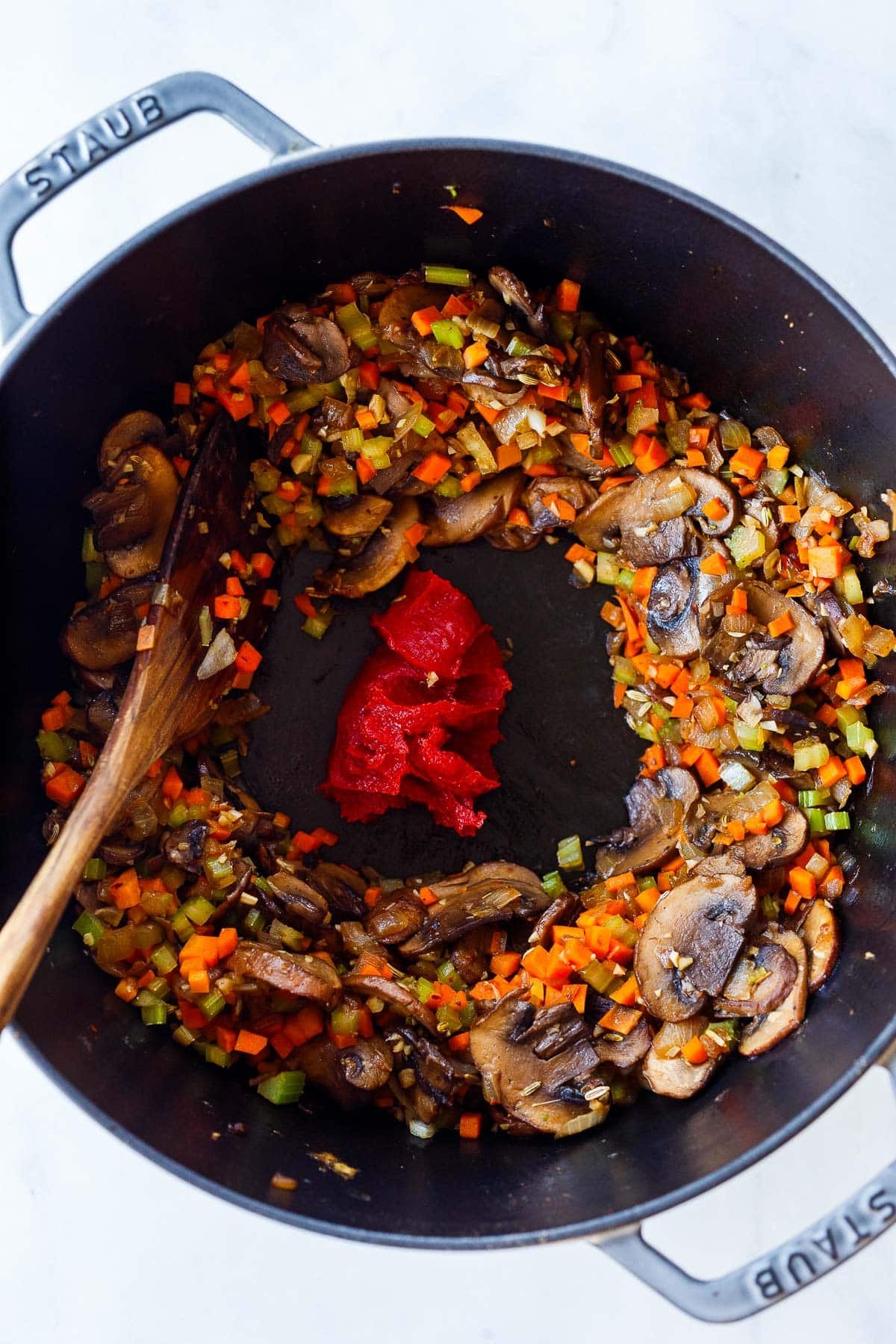 sautéed mushrooms, carrots, and celery with a well in the center with tomato paste.