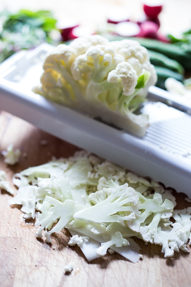 Shaved Cauliflower Salad with spring peas, radishes, cucumber, mint and a delicious Yogurt Dressing. The thinly sliced cauliflower is raw and marinates in the flavorful dressing. #cauliflowersalad #springsalad #yogurtdressing #raw #rawsalad 