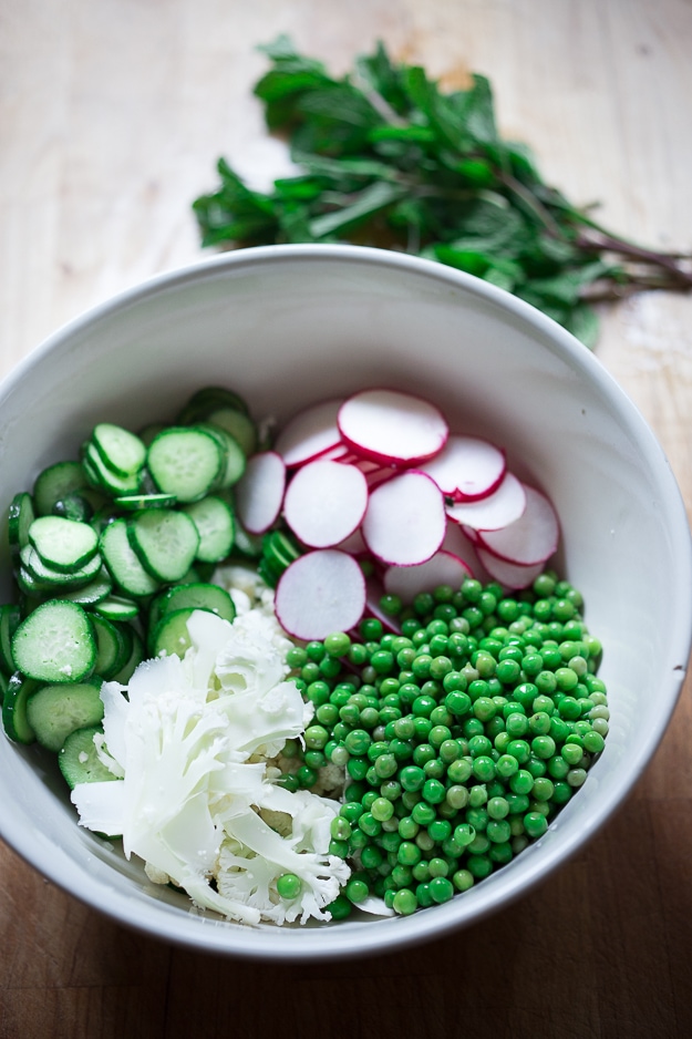 Shaved Cauliflower Salad with spring peas, radishes, cucumber, mint and a delicious Yogurt Dressing. The thinly sliced cauliflower is raw and marinates in the flavorful dressing. #cauliflowersalad #springsalad #yogurtdressing #raw #rawsalad 