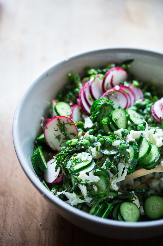Shaved Cauliflower Salad with spring peas, radishes, cucumber, mint and a delicious Yogurt Dressing. The thinly sliced cauliflower is raw and marinates in the flavorful dressing. #cauliflowersalad #springsalad #yogurtdressing #raw #rawsalad 