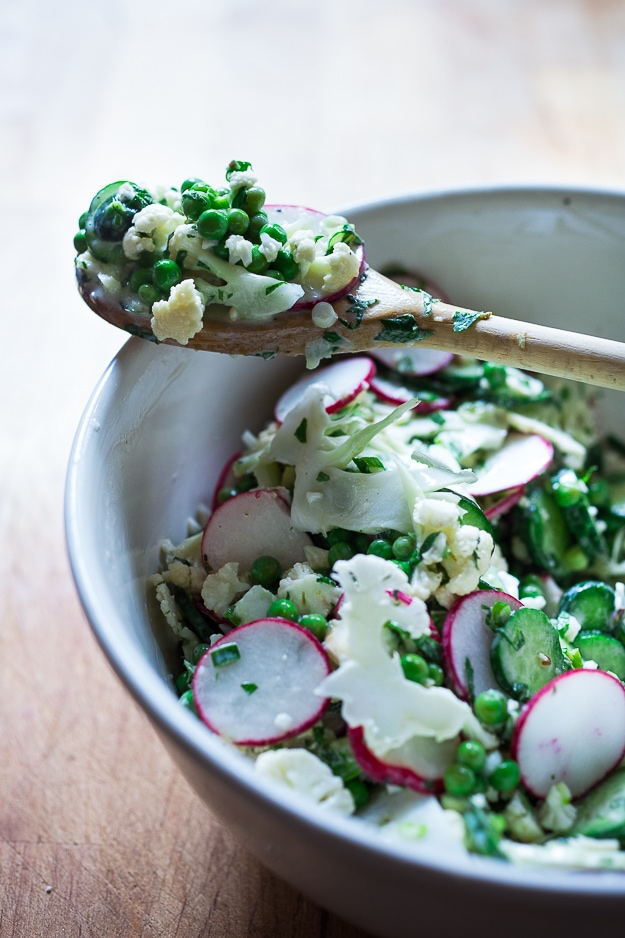 Shaved Cauliflower Salad with spring peas, radishes, cucumber, mint and a delicious Yogurt Dressing. The thinly sliced cauliflower is raw and marinates in the flavorful dressing. #cauliflowersalad #springsalad #yogurtdressing #raw #rawsalad 