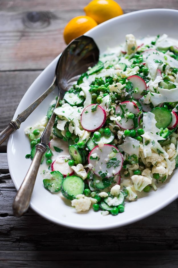 Shaved Cauliflower Salad with spring peas, radishes, cucumber, mint and a delicious Yogurt Dressing. The thinly sliced cauliflower is raw and marinates in the flavorful dressing. #cauliflowersalad #springsalad #yogurtdressing #raw #rawsalad 
