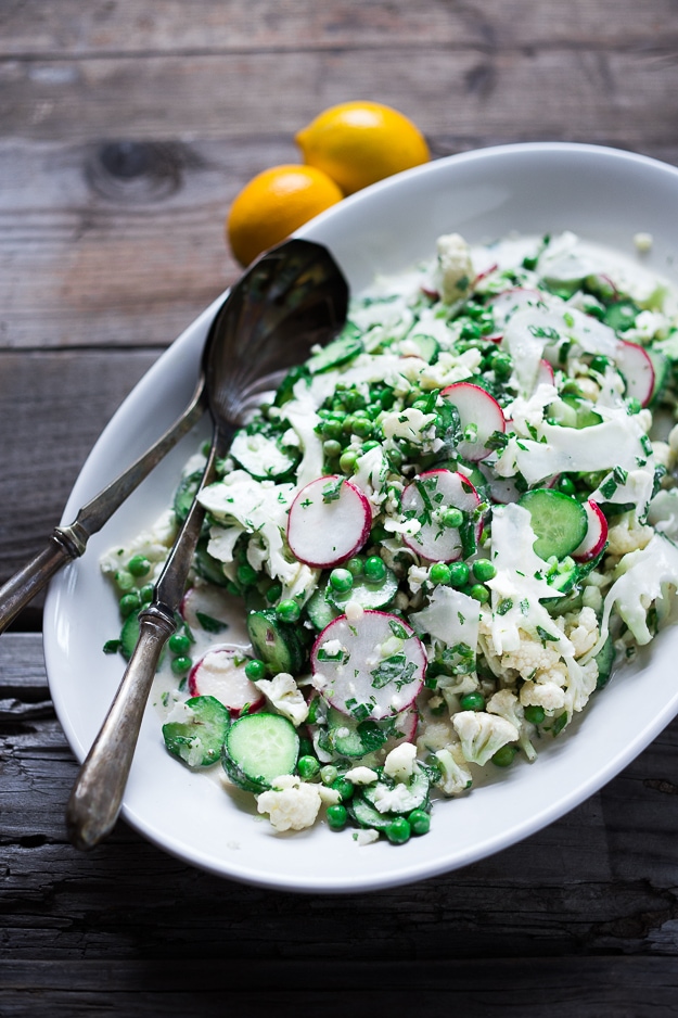 Shaved Cauliflower Salad with spring peas, radishes, cucumber, mint and a delicious Yogurt Dressing. The thinly sliced cauliflower is raw and marinates in the flavorful dressing. #cauliflowersalad #springsalad #yogurtdressing #raw #rawsalad 