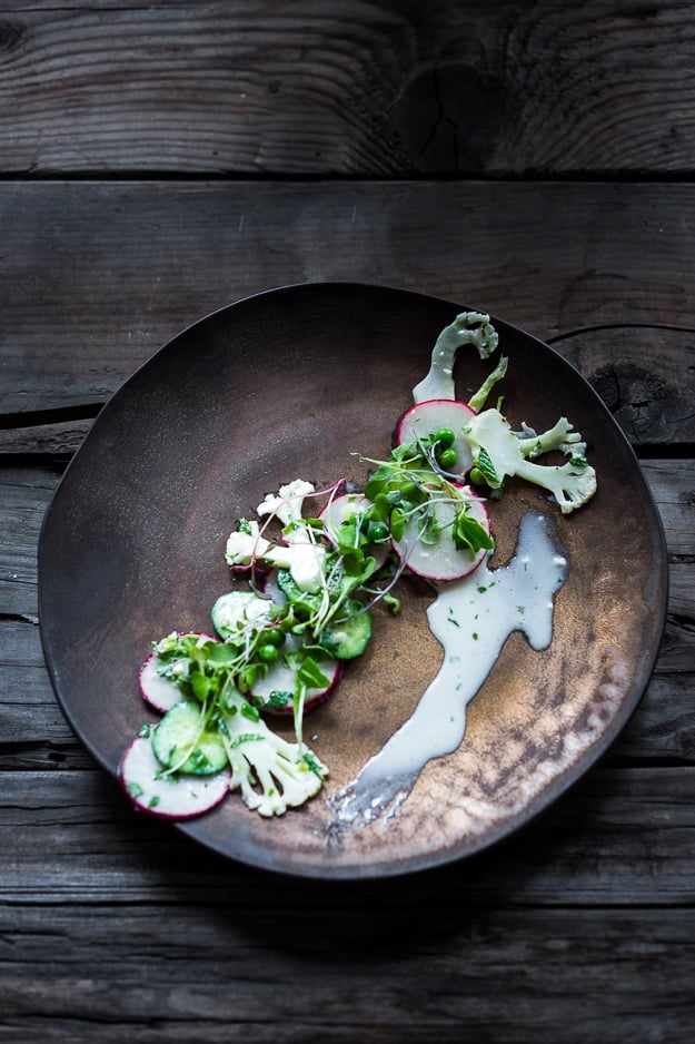 Shaved Cauliflower Salad with spring peas, radishes, cucumber, mint and a delicious Yogurt Dressing. The thinly sliced cauliflower is raw and marinates in the flavorful dressing. #cauliflowersalad #springsalad #yogurtdressing #raw #rawsalad