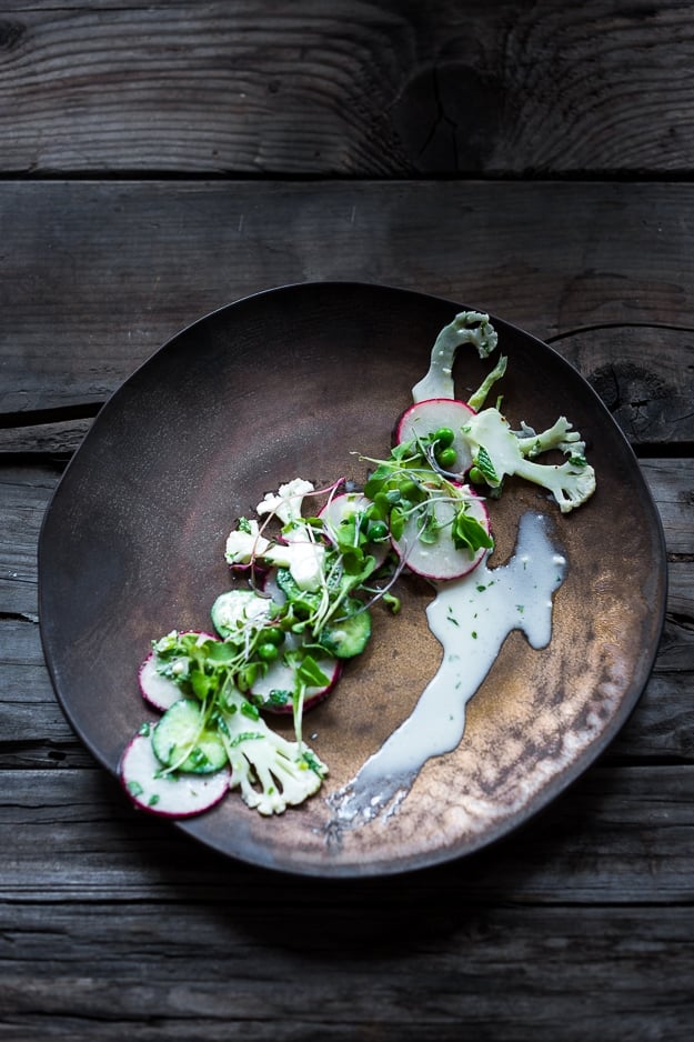 Shaved Cauliflower Salad with spring peas, radishes, cucumber, mint and a delicious Yogurt Dressing. The thinly sliced cauliflower is raw and marinates in the flavorful dressing. #cauliflowersalad #springsalad #yogurtdressing #raw #rawsalad 