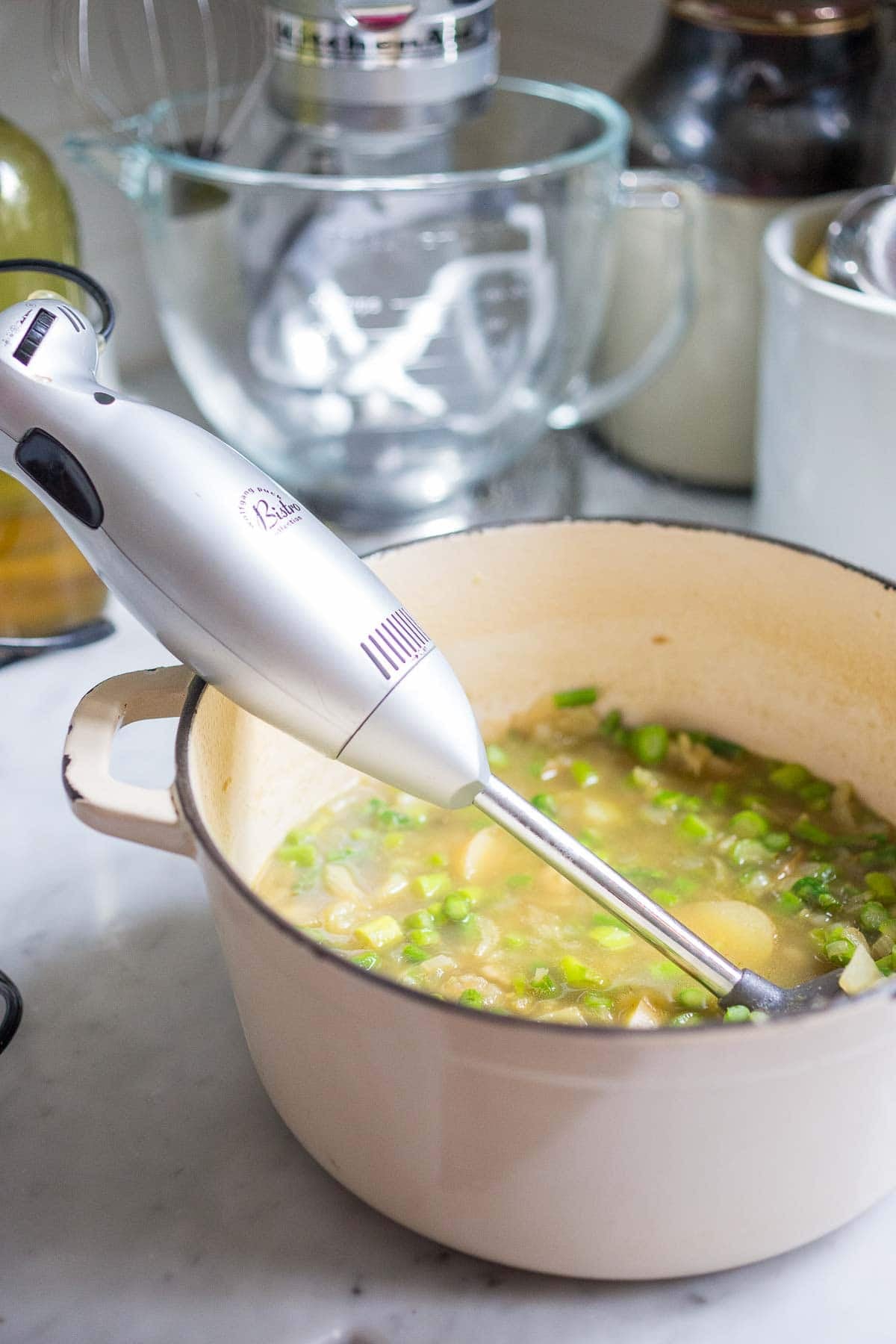 Dutch oven with simmered asparagus, potatoes, and broth with immersion blender.