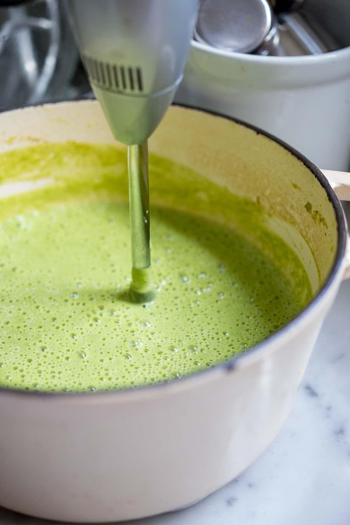 immersion blender in pot of creamy asparagus soup.