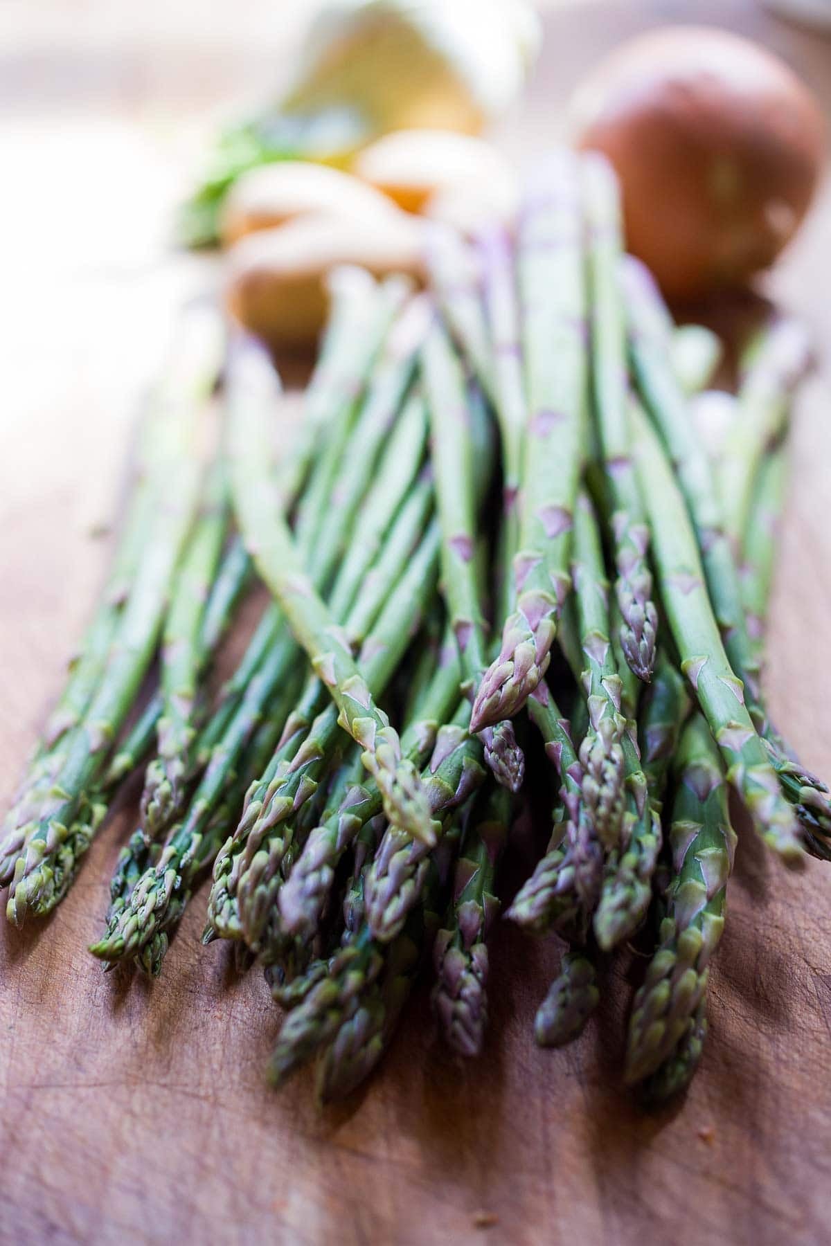 bunch of fresh spring asparagus on wood board.