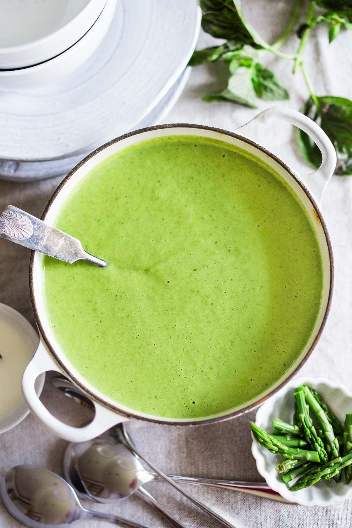 Dutch oven with creamy asparagus soup with silver ladle.