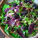 A simple recipe for Blackberry Salad with Basil and Arugula sprinkled with crumbled goat cheese, toasted almonds and a maple-balsamic dressing. A light and delicious summer salad! #blackberry #blackberrysalad