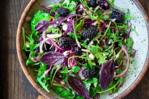 A simple recipe for Blackberry Salad with Basil and Arugula sprinkled with crumbled goat cheese, toasted almonds and a maple-balsamic dressing. A light and delicious summer salad! #blackberry #blackberrysalad