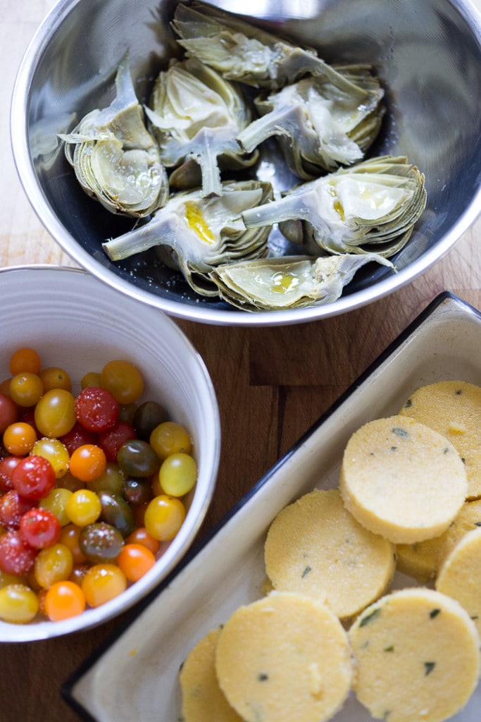 Grilled Artichokes and Polenta with Blistered tomatoes, pesto, capers and fresh basil-- served family style ...perfect for a casual summer evening! Vegan and GF | www.feastingathome.com| #grilledartichokes