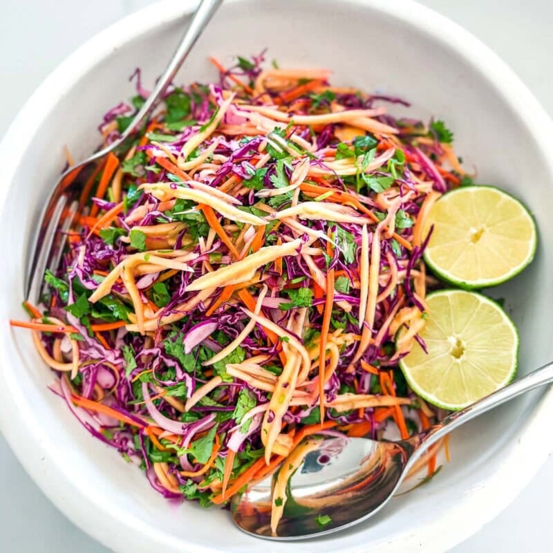 This mango slaw recipe is so refreshing and light! Made with fresh mango, crunchy purple cabbage, red onion, cilantro, and lime, this salad is the perfect summer treat and makes a delicious topping for tacos, bowls, and more!
