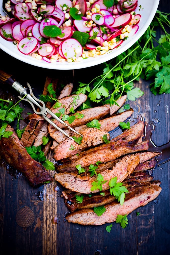 grilled flank steak, sliced on a wood board with cilantro.