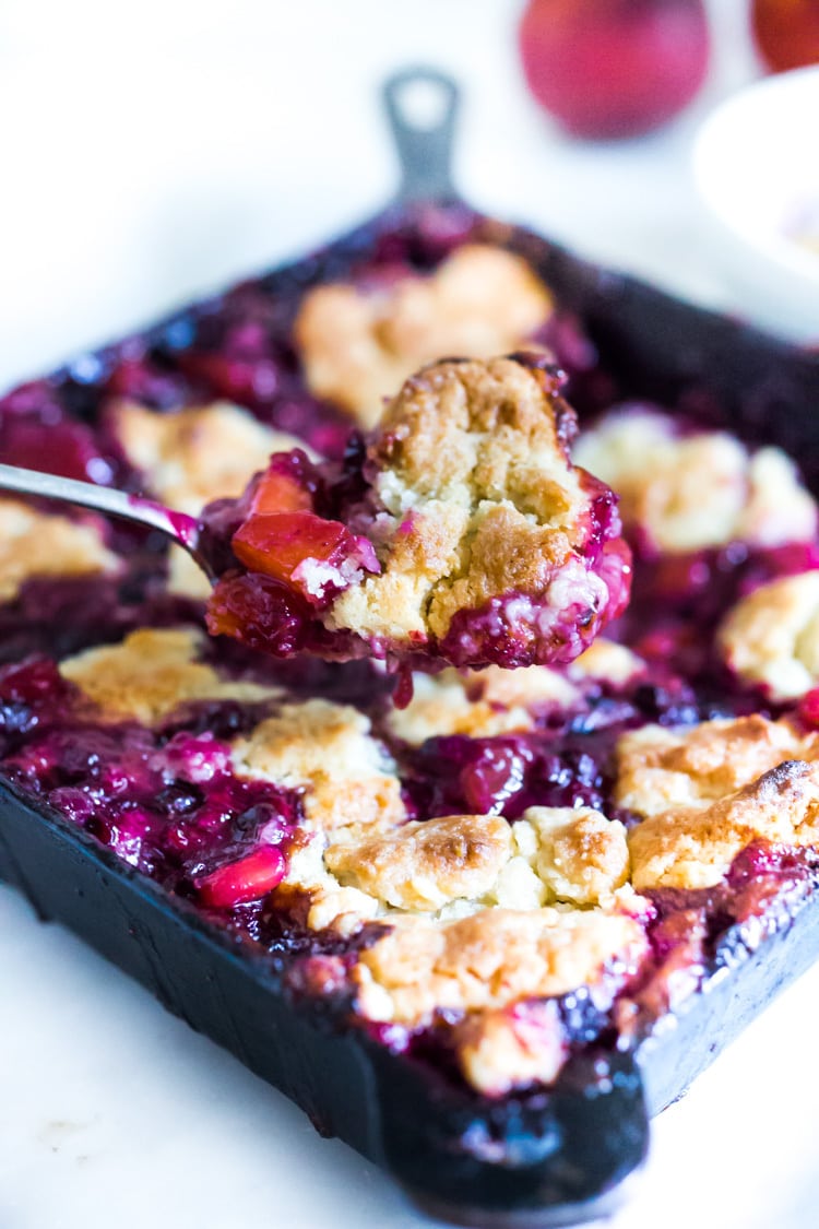 This Peach Skillet Cobbler is topped with a golden and delicious, biscuit topping with fresh summer peaches and berries. This can be made gluten-free and or vegan! #peachcobbler #skilletcobbler #summer #desserts #peachdesserts #huckleberries #vegancobler #glutenfreecobbler #vegandessert 