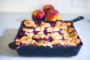 How to make skillet cobbler with fresh summer peaches and optional huckleberries. Use other summer berries, like black berries or blueberries! This can be made gluten-free and or vegan! 