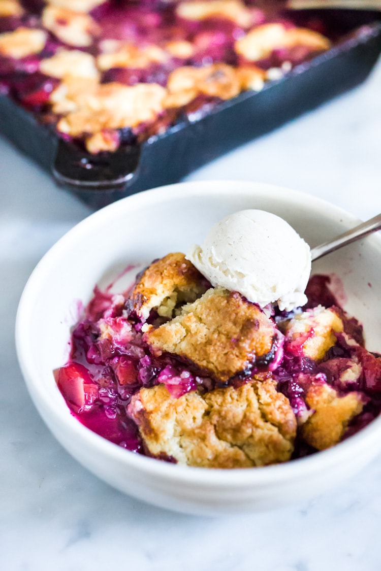 This Peach Skillet Cobbler is topped with a golden and delicious, biscuit topping with fresh summer peaches and berries. This can be made gluten-free and or vegan! #peachcobbler #skilletcobbler #summer #desserts #peachdesserts #huckleberries #vegancobler #glutenfreecobbler #vegandessert 