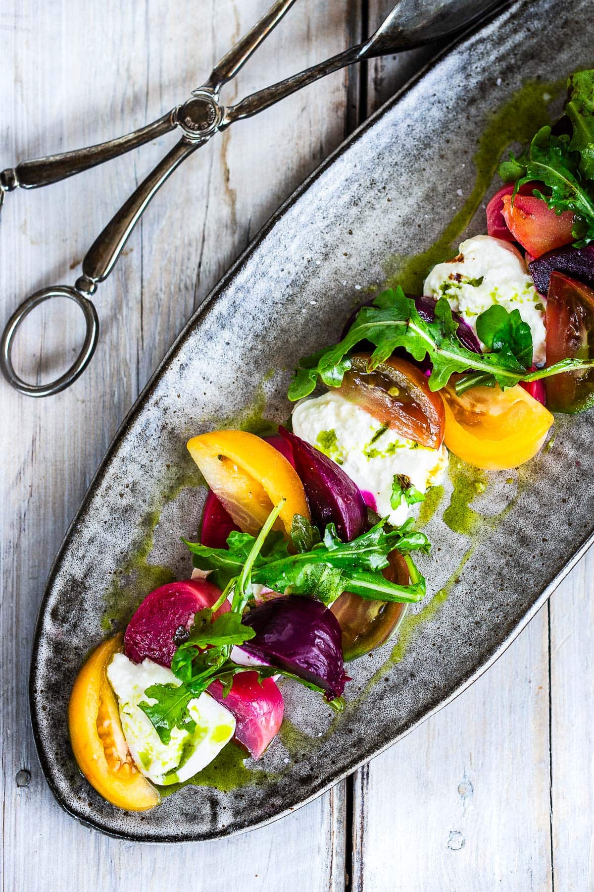 A beautiful Burrata Salad with tomatoes, beets, basil and flavorful basil oil, drizzled with balsamic glaze - perfect for summer dinners and gatherings. Elegant and flavorful.