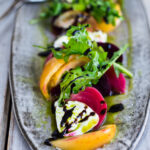 Creamy Burrata is paired with summer tomatoes, beets, and fresh basil- a delicious summery appetizer or salad, perfect for special gatherings.