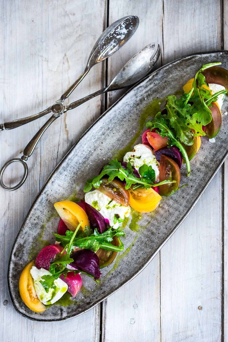 Creamy Burrata is paired with summer tomatoes, beets, and fresh basil- a delicious summery appetizer or salad, perfect for special gatherings.