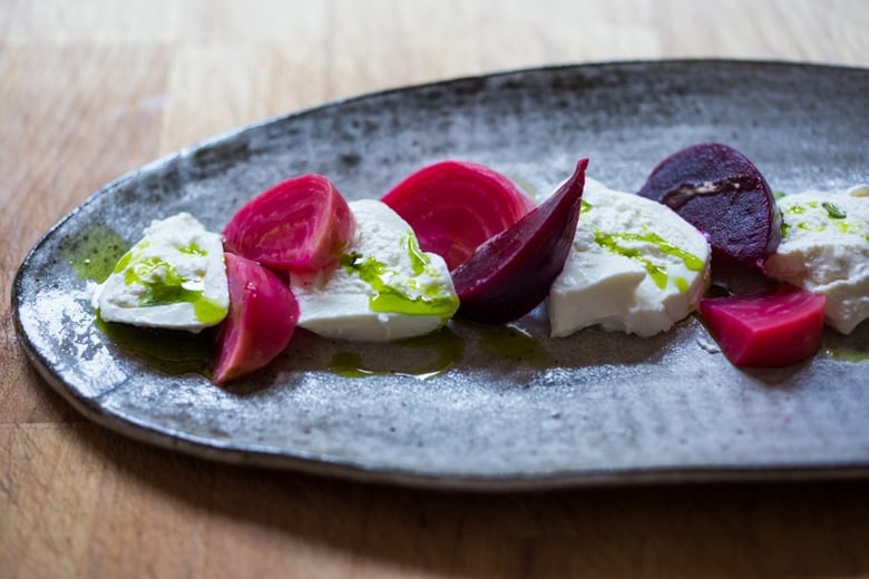 arranging the burrata, tomatoes, and beets on a platter.