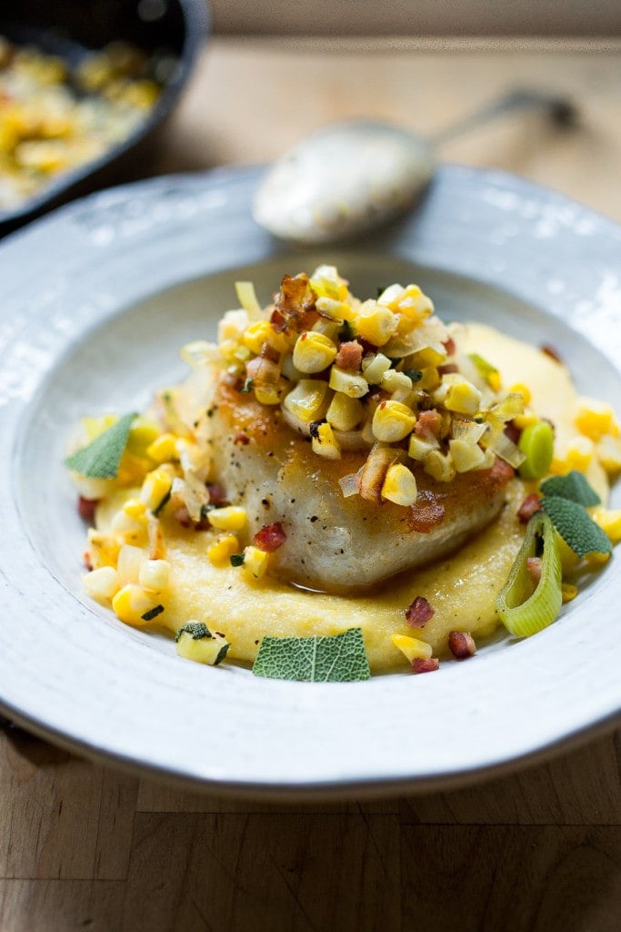 Seared Halibut serving plate with halibut with fresh corn and leeks and fresh sage over creamy polenta.