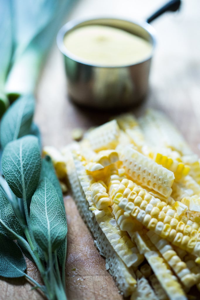 freshly sliced corn and a bunch of fresh sage laid out on wood surface.