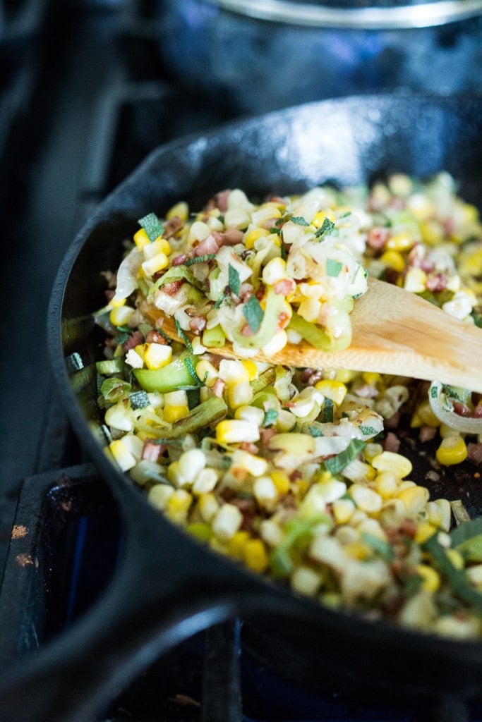 cast iron skillet with fresh corn and leek mixture with pancetta and sage.