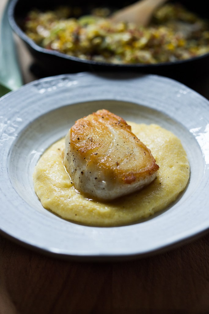 serving bowl with creamy polenta topped with seared halibut.