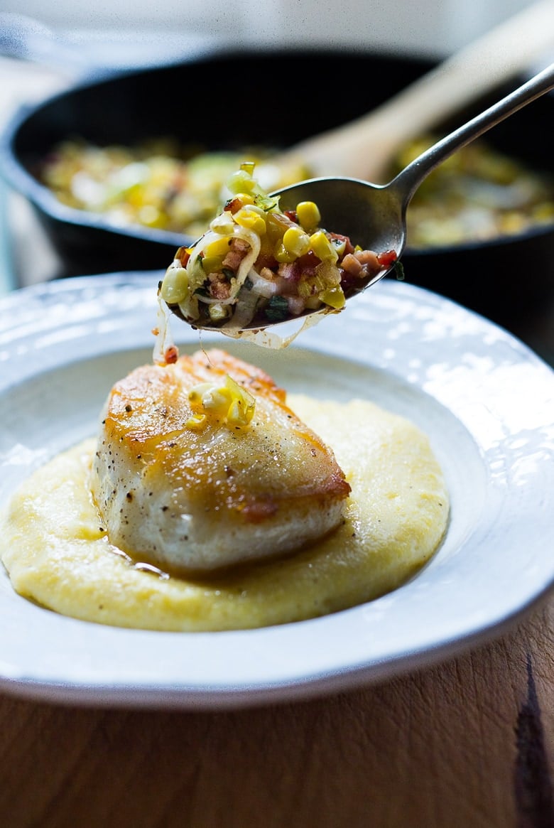 spooning corn leek mixture over seared halibut on top of creamy polenta.