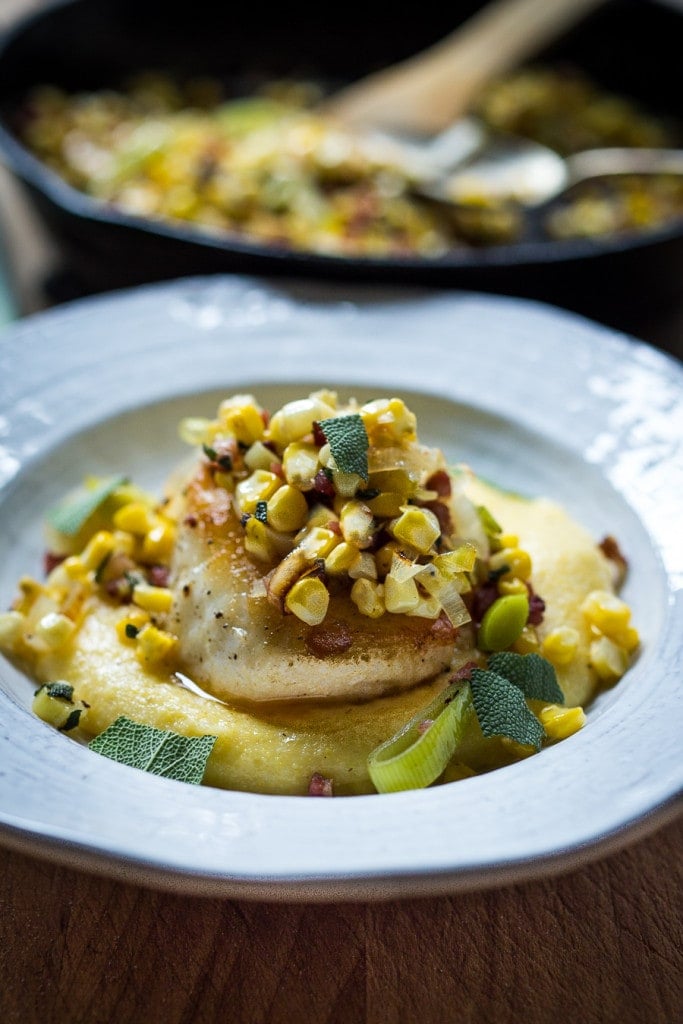 creamy polenta topped with seared halibut with fresh corn and leeks and sage scattered over top.