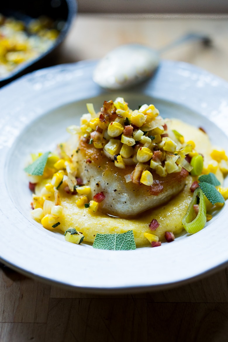 A simple delicious recipe for Halibut with corn, pancetta and sage, served over a "lightened-up" creamy polenta. And the best part is it can be made un under 30 minutes! | www.feastingathome.com