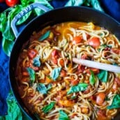 spaghetti in a skillet with fresh tomato sauce and basil.