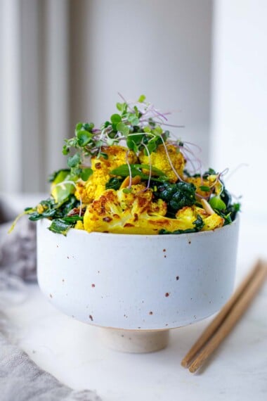 This Roasted Cauliflower Salad recipe is incredibly flavorful. Cauliflower is roasted until tender-crisp, then tossed with farro, lacinato kale, scallions, raisins, and toasty almonds in a savory-sweet turmeric dressing. Vegan.